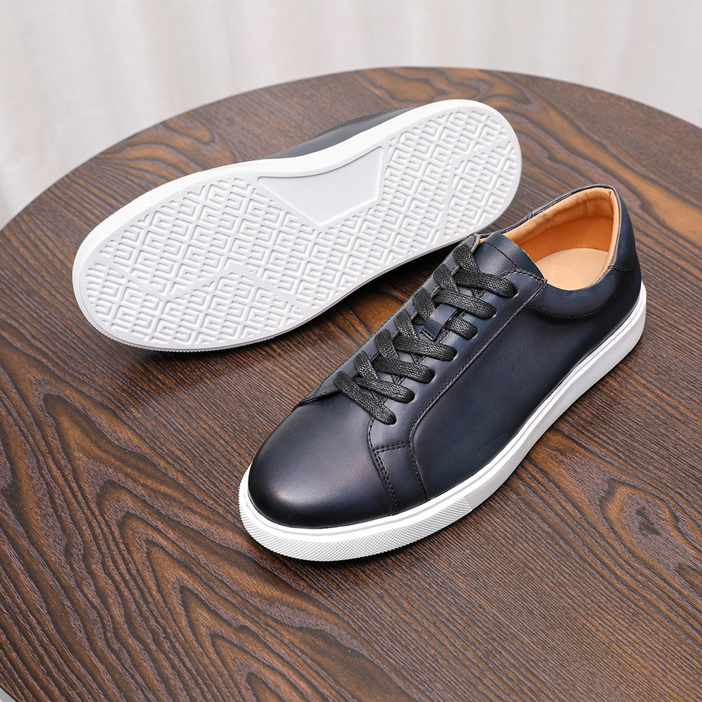 Men's dark leather sneakers with white treaded outsole and orange lining, top view