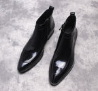 Black leather side-zip dress boots with pointed toe and stitched paneling