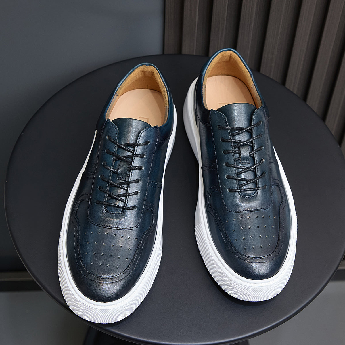 Men's navy leather lace-up sneakers with white rubber sole and perforated toe
