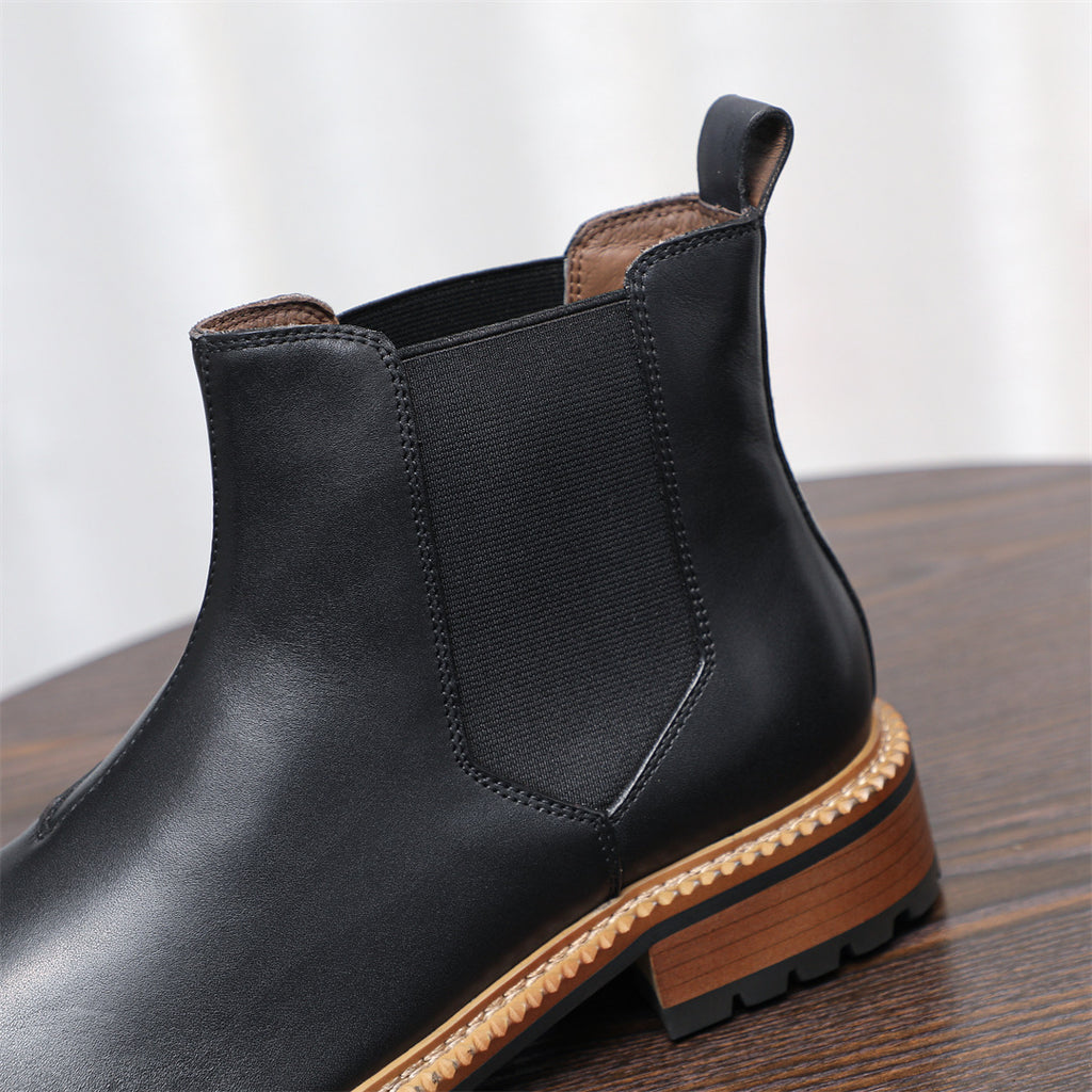 Close-up of black Chelsea boot shaft with elastic side panel and tan welt trim