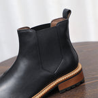 Close-up of black Chelsea boot shaft with elastic side panel and tan welt trim