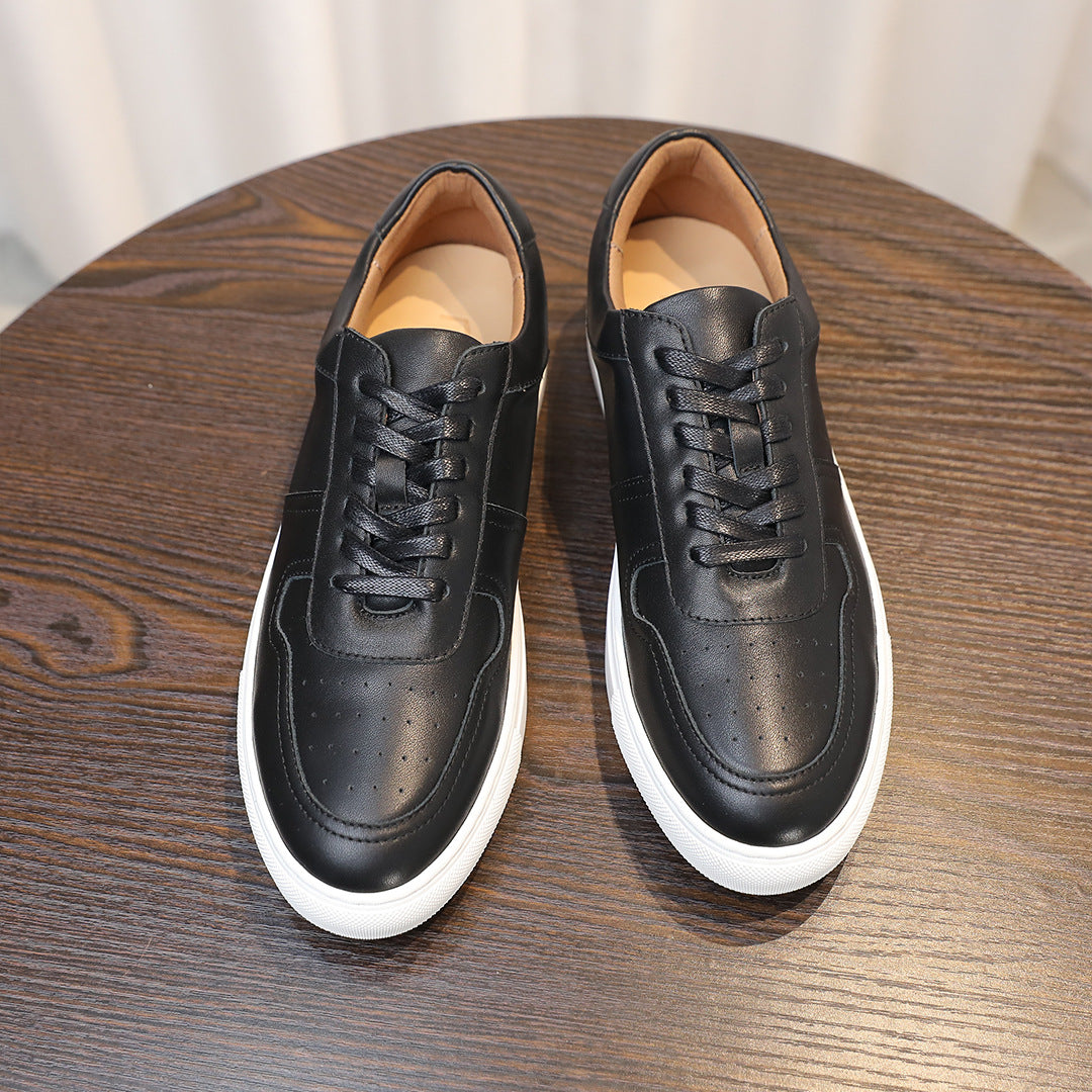 Pair of black leather sneakers, lace-up front view with white sole and perforated toe