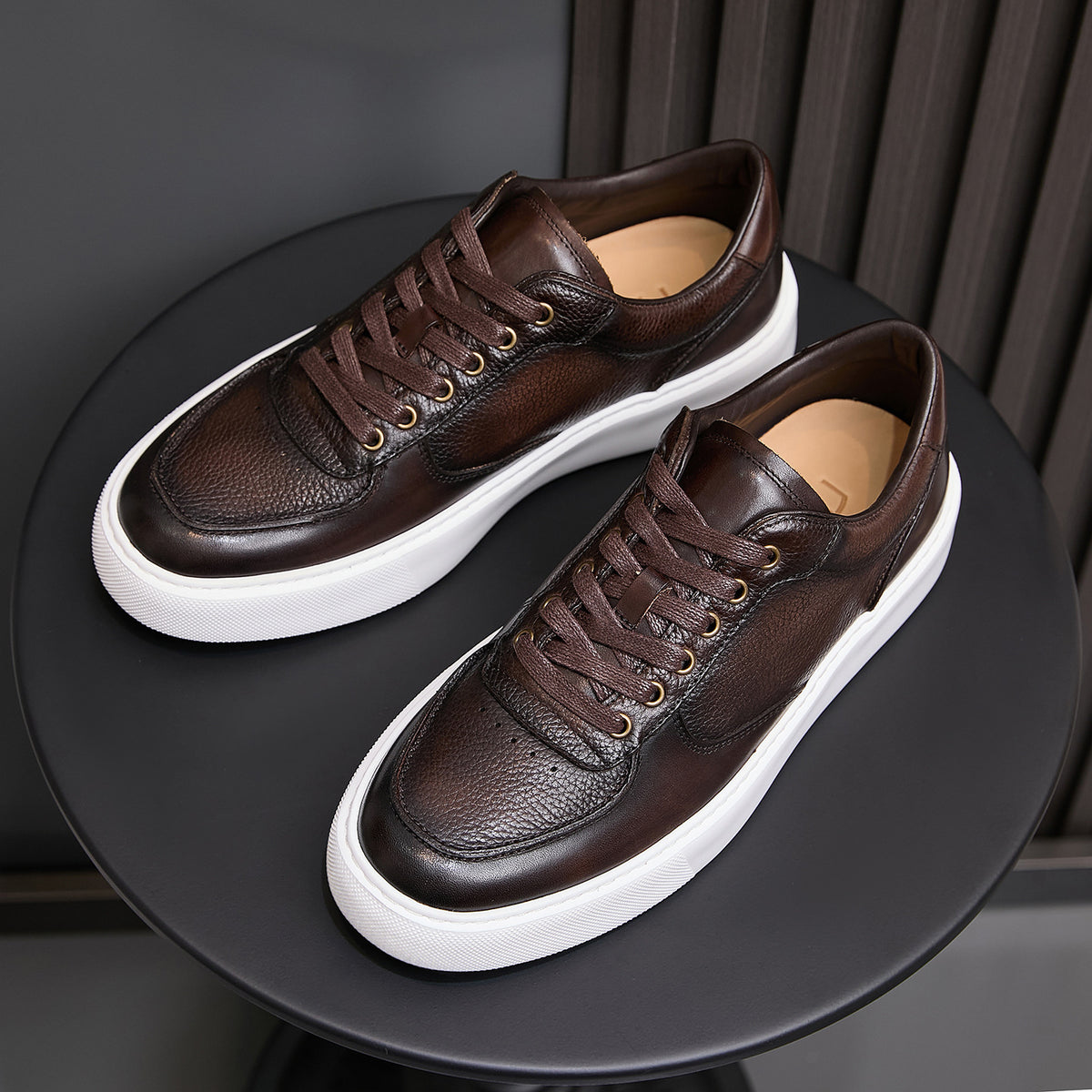 Men's dark brown leather lace-up sneakers with gold-toned eyelets and white rubber sole