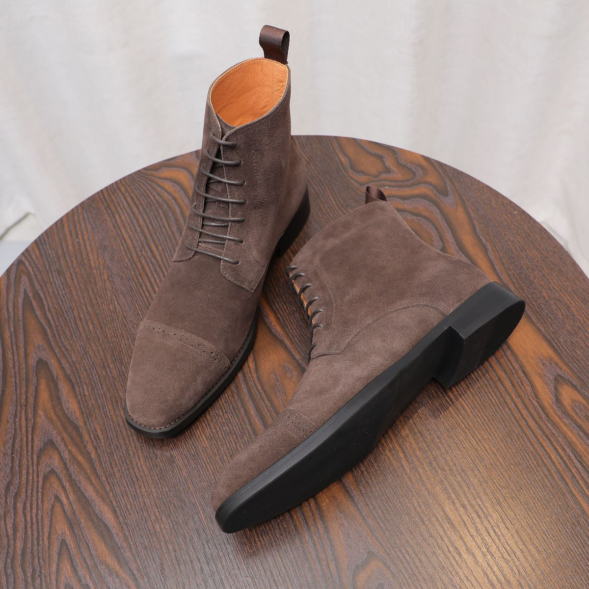 Dark brown suede chukka boots, side angle view with lace-up closure and black sole