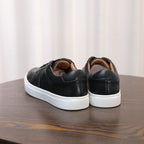 Men's black leather sneakers from the heel, showing cushioned collar and white sole