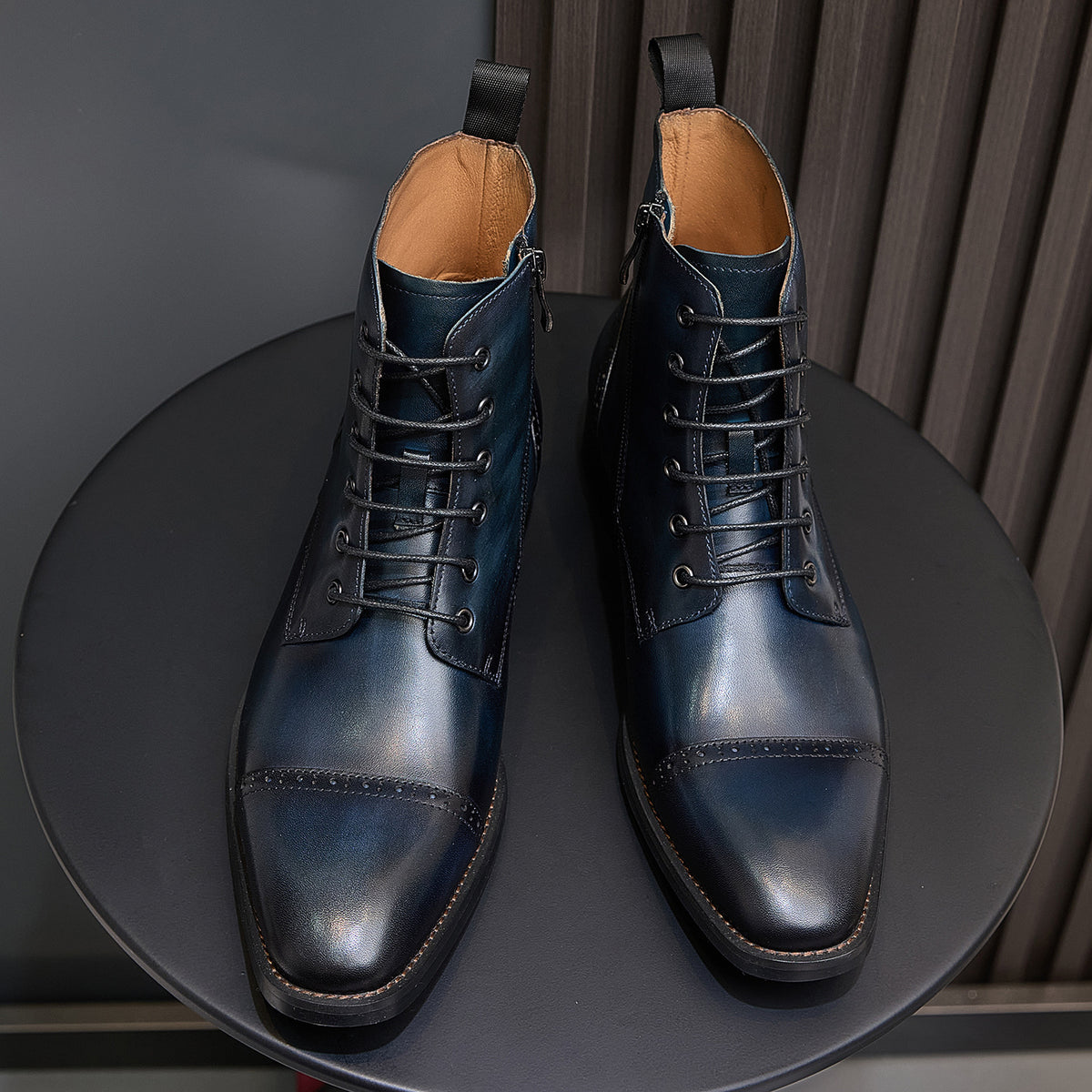 Two lace-up leather ankle boots with dark blue finish, pointed toe and tan lining.