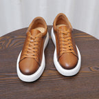 Men's brown leather lace-up sneakers, two shoes front view with white soles