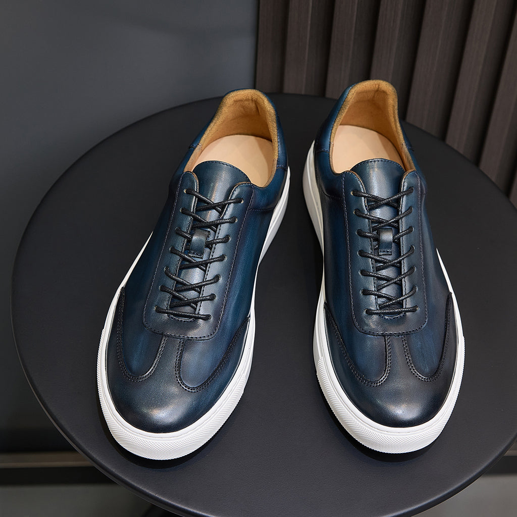 Front view of men's blue leather sneakers with black laces, white sole, and tan lining.
