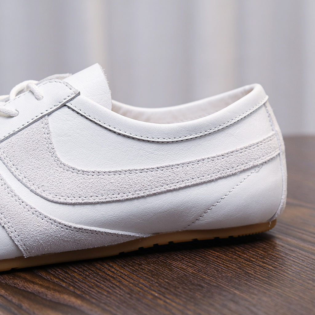 Men's white leather sneaker with stitched panels, lace eyelets, and padded collar