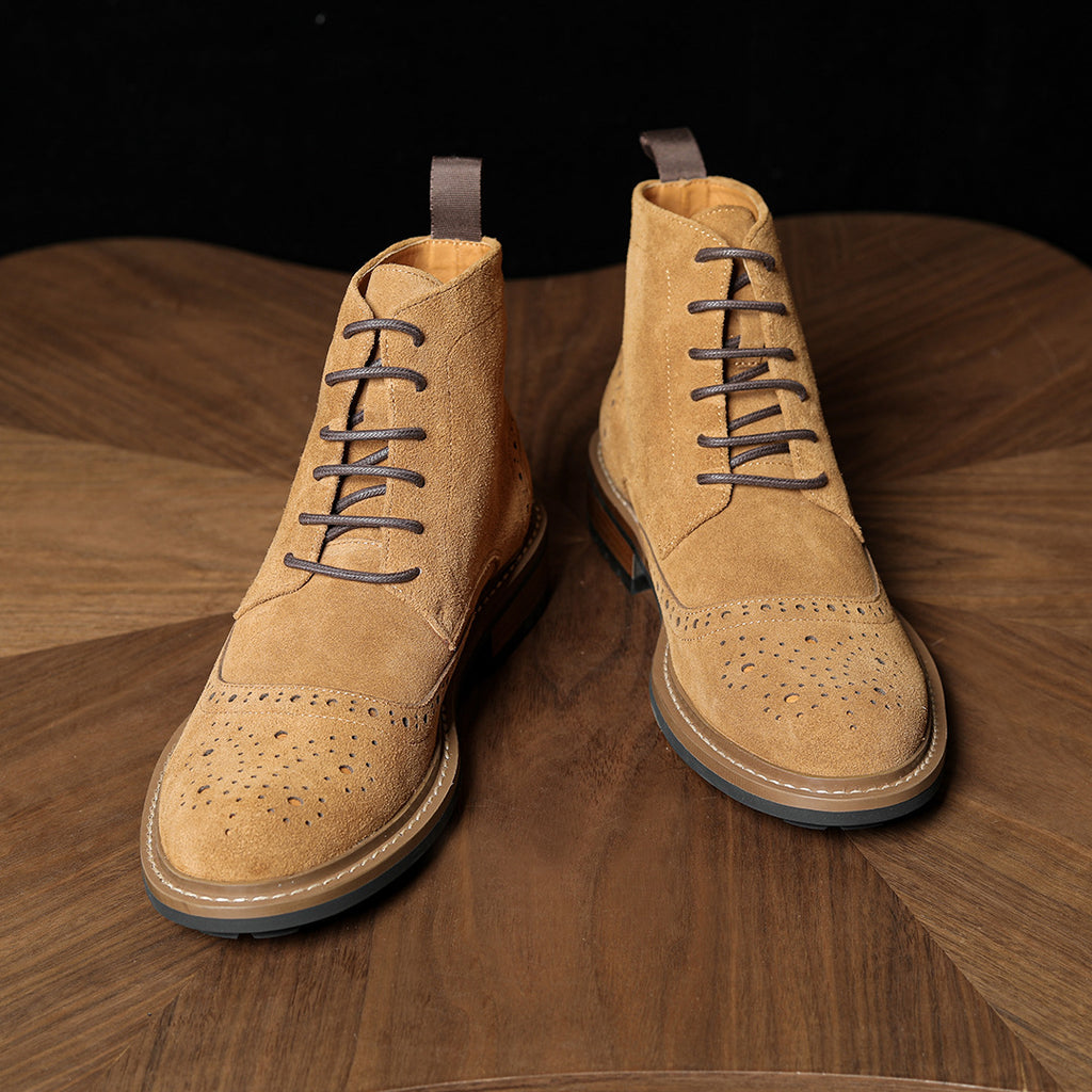 Tan leather chukka boots shown from front, lace-up eyelets, perforation pattern on toe and sides