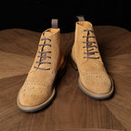 Tan leather chukka boots shown from front, lace-up eyelets, perforation pattern on toe and sides