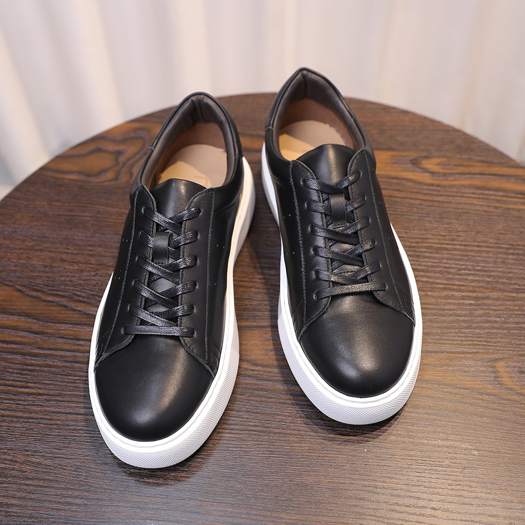 Pair of men's black leather sneakers with lace-up front and white rubber sidewalls