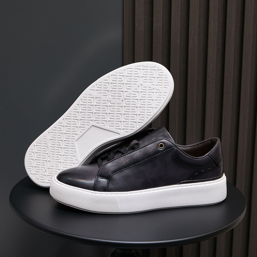 Black leather sneakers showing white outsole with grid tread pattern
