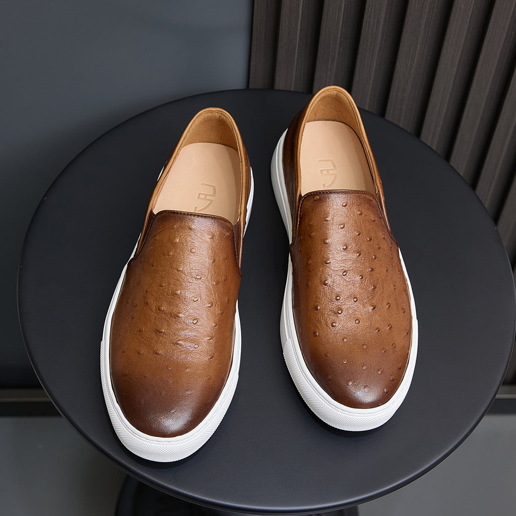Pair of brown leather slip-on sneakers with perforations, tan lining, and white sole