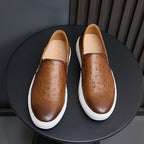 Pair of brown leather slip-on sneakers with perforations, tan lining, and white sole