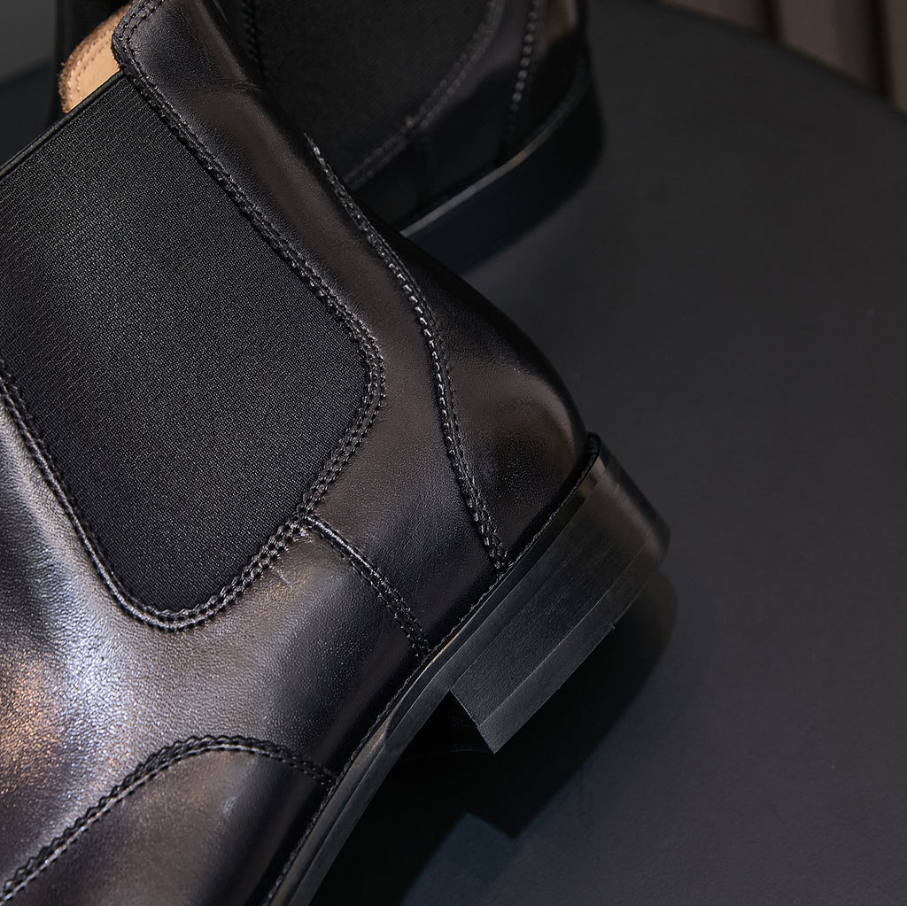 Close-up of men's black chelsea boot heel and elastic side panel with stitched edge