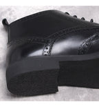Black lace-up dress boots with chunky sole and wingtip detailing