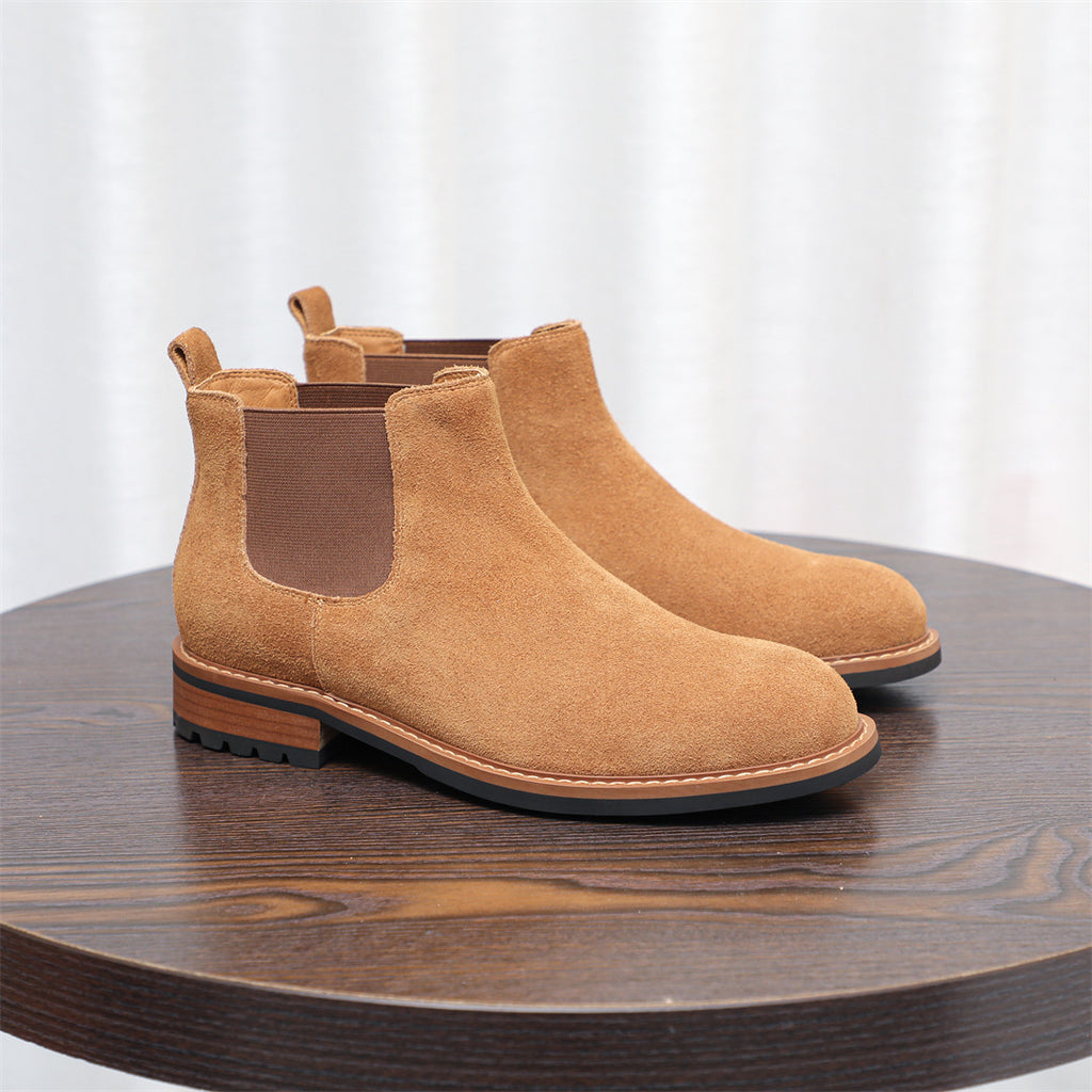Tan suede pointed-toe Chelsea dress boots with elastic side panels and flat sole.