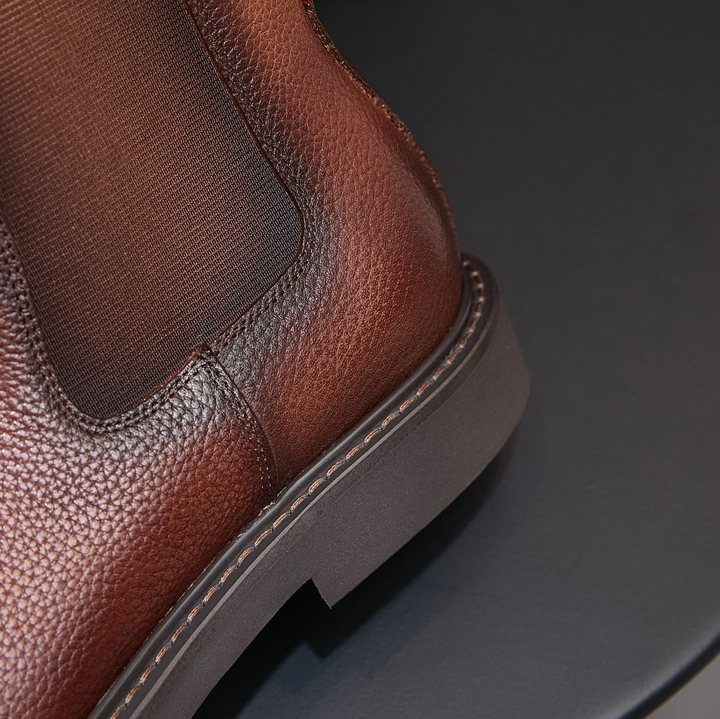 Brown Chelsea dress boots close-up showing side elastic gore and sole edge stitching