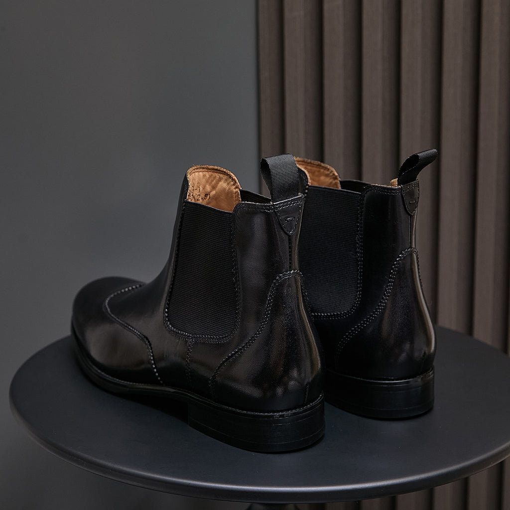 Back view of men's pointed-toe black chelsea boots with pull tabs and stacked heel