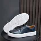 Men's navy leather sneakers with textured white outsole tread and white sidewall sole