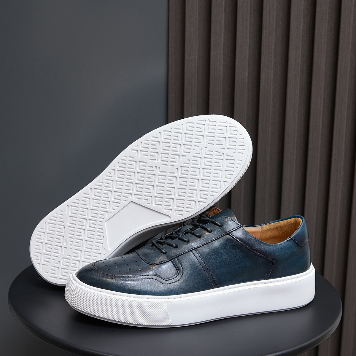 Men's navy leather sneakers with textured white outsole tread and white sidewall sole