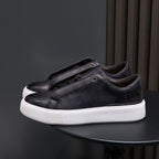 Black leather low-top sneakers with white midsole and lace-up front