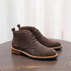 Dark brown lace-up chukka boots with low heel, suede upper, side profile.