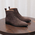 Dark brown suede chukka boots pair, front angle with lace-up and black rubber sole