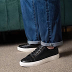 Black genuine leather lace-up sneakers with white rubber sole; worn with jeans