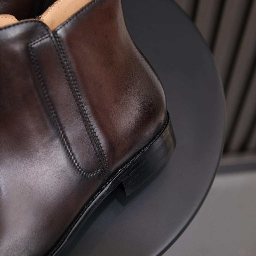 Side view of men's dark brown leather dress boots showing side zip and stitched trim.