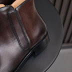 Side view of men's dark brown leather dress boots showing side zip and stitched trim.