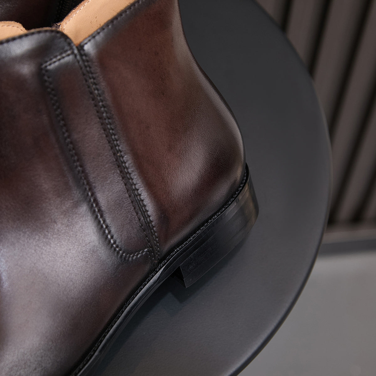Side view of men's dark brown leather dress boots showing side zip and stitched trim.