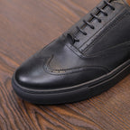Black leather sneaker toe with lace eyelets, side panel stitching, and low profile
