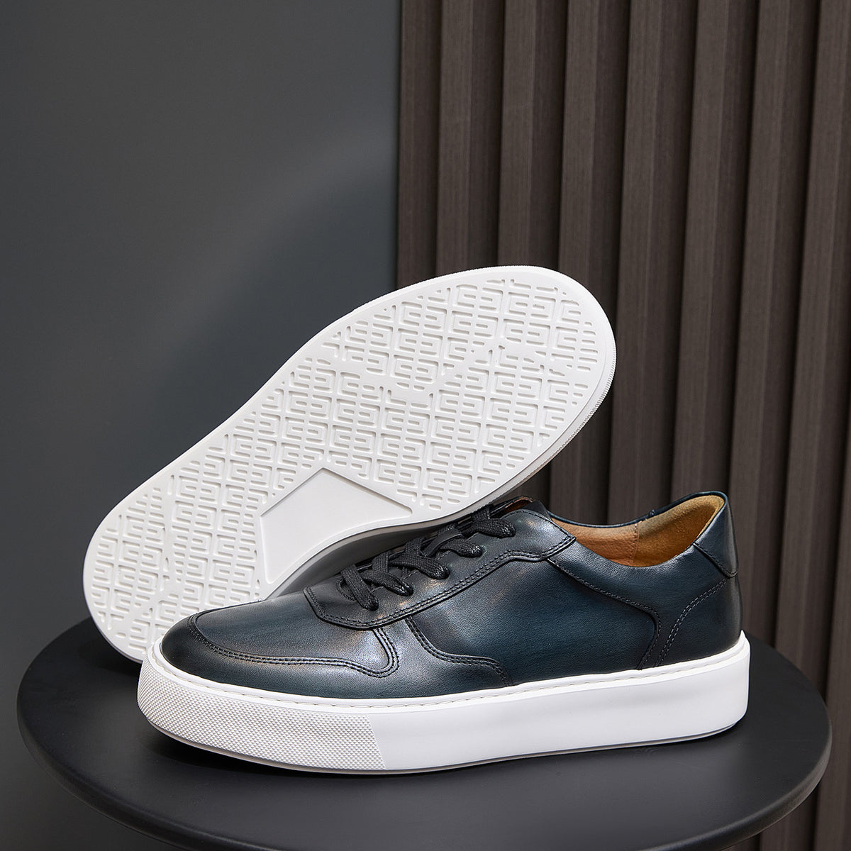 Men's leather sneaker outsole with textured tread, dark blue upper and white sole.