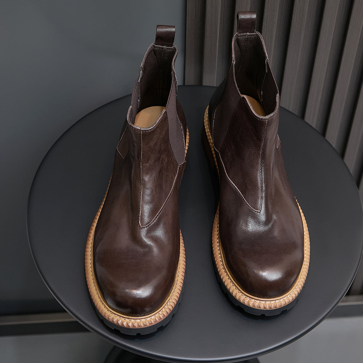 Pair of dark brown suede Chelsea boots with elastic side panels and tan rubber sole