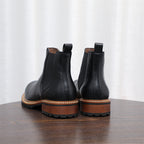 Pair of black pointed-toe Chelsea boots showing back pull tabs and lug sole
