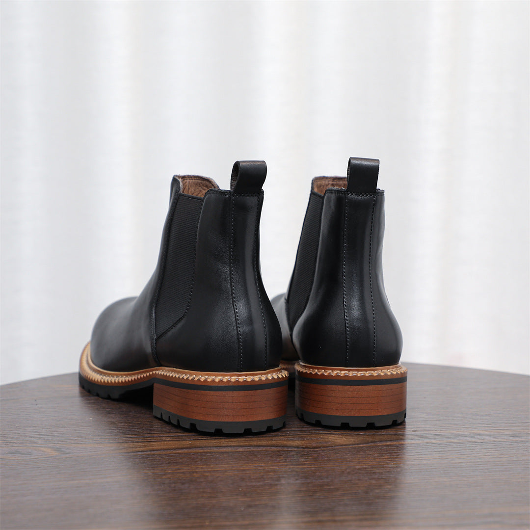 Pair of black pointed-toe Chelsea boots showing back pull tabs and lug sole