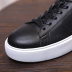 Black leather low-top sneaker toe with lace eyelets and white textured sole