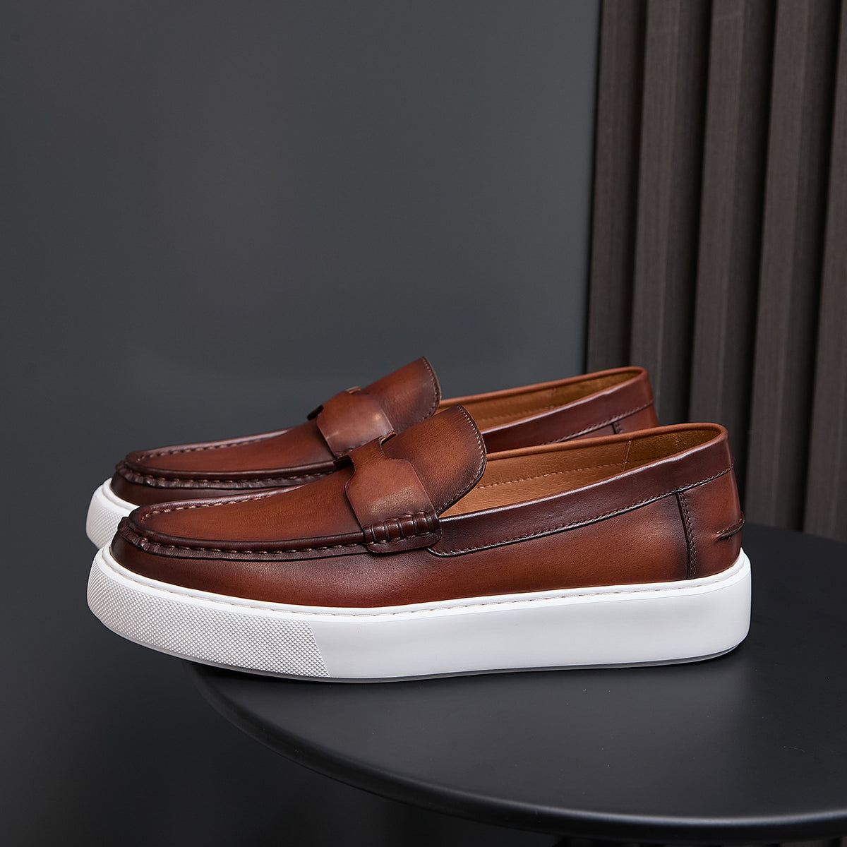 Men's brown leather slip-on sneakers with tassel-free moc toe and white platform sole.