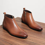 Pair of brown leather ankle boots with side zippers and thick rubber soles.