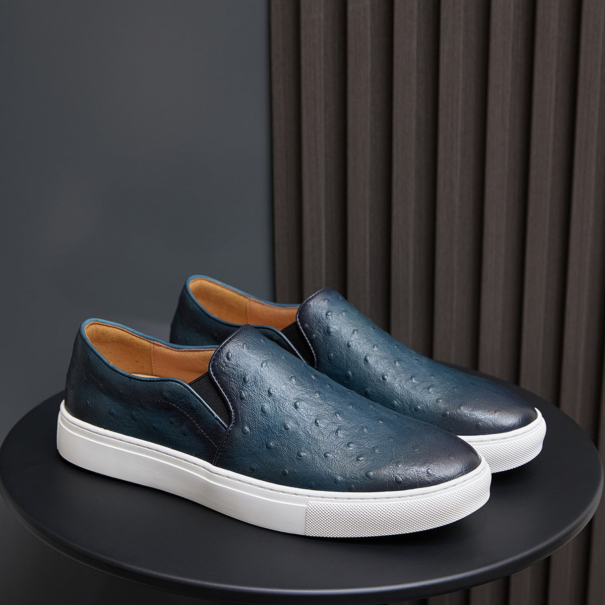 Men's dark blue slip-on leather sneakers with white rubber sole and textured upper
