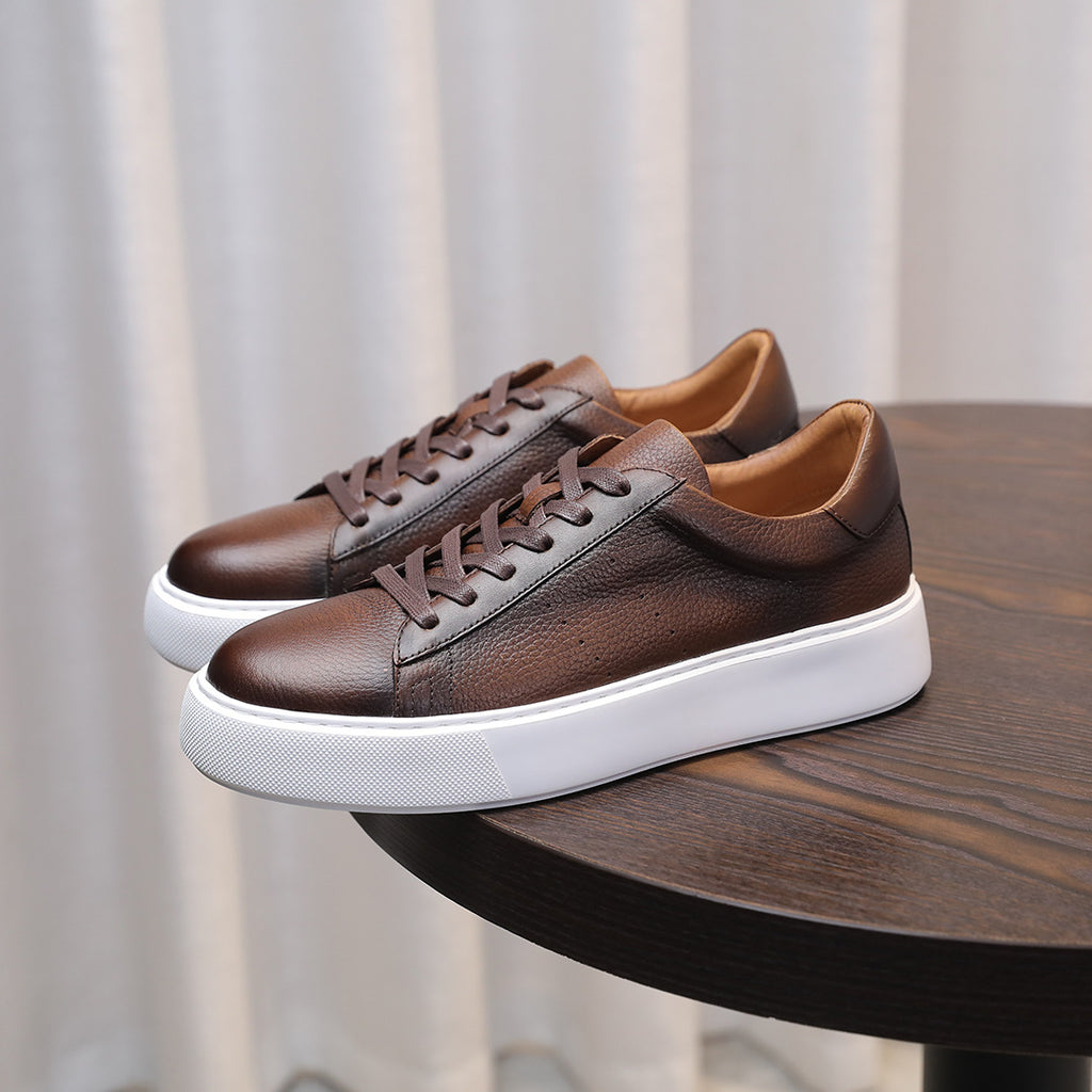 Dark brown leather low-top sneakers with lace-up front and thick white sole.