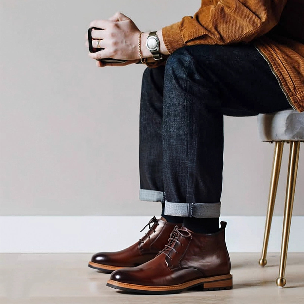 Men's brown leather chukka boots with lace-up closure, plain toe, worn with dark jeans