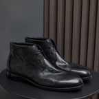 Black leather lace-up chukka boots, side view with eyelets and stitched seam.