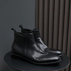 Black leather pointed-toe side-zip boots on a tray with stitched welt