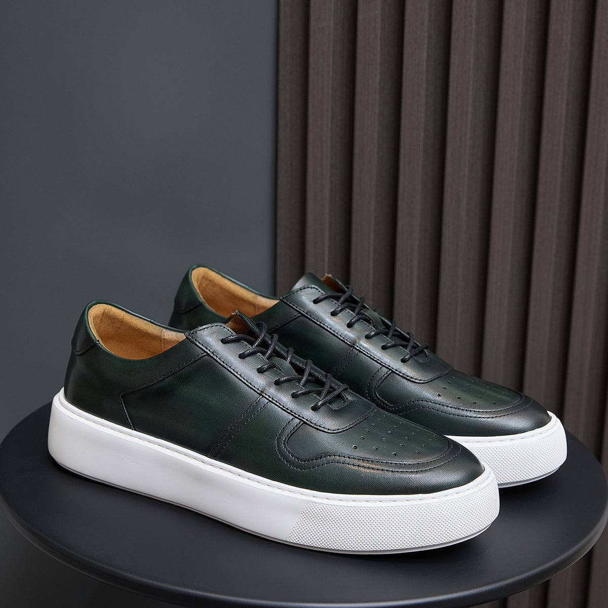 Leather sneakers in dark green, lace-up style with white rubber sole and side panels.