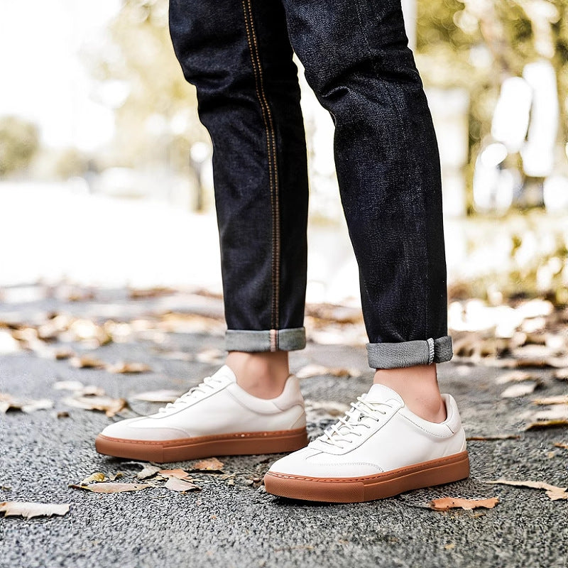 White leather sneakers with tan rubber sole and lace-up design