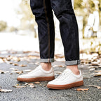 White leather sneakers with tan rubber sole and lace-up design