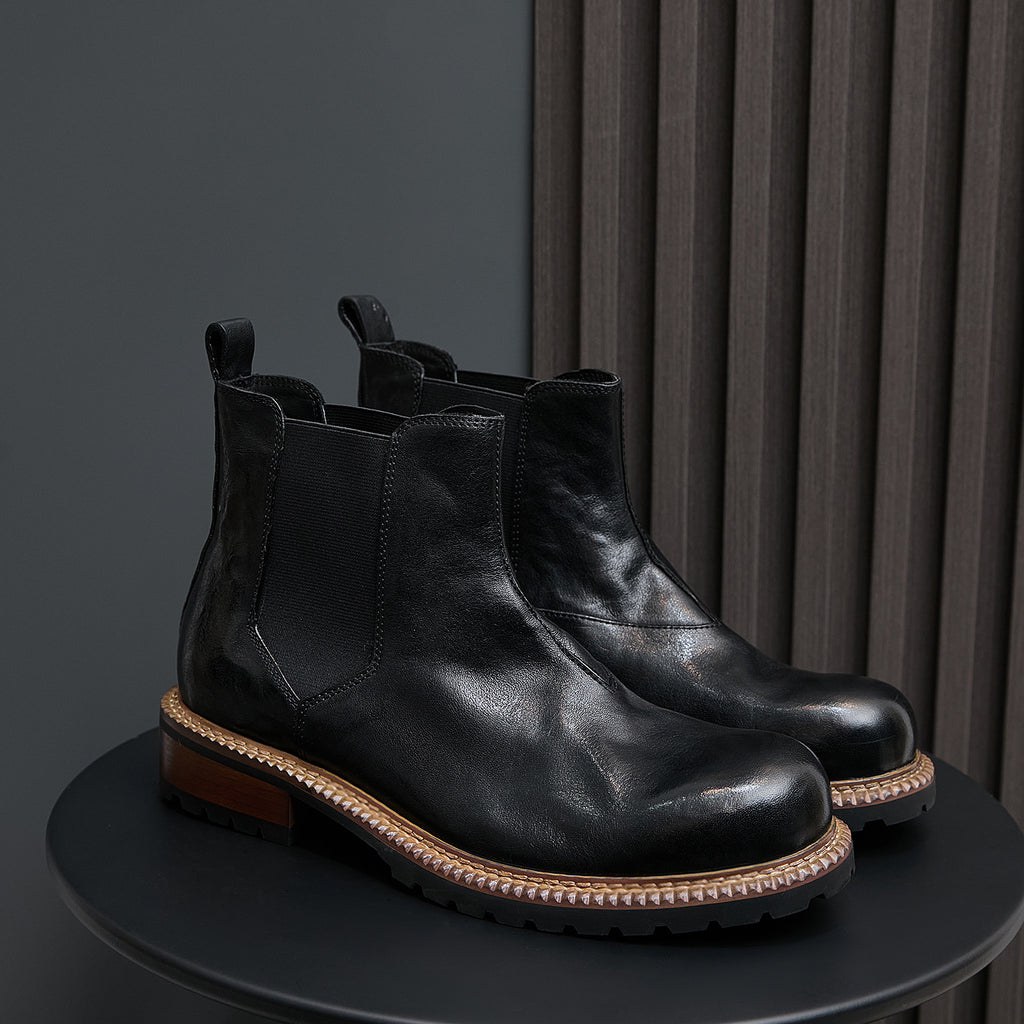 Men's pointed-toe suede Chelsea dress boots, black, pair on display with side elastic panels